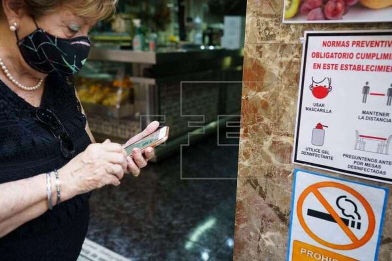 Una mujer busca en su móvil su certificado Covid momentos antes de acceder al interior de una cafetería de Santa Cruz de Tenerife / EFE Ramón de la Rocha